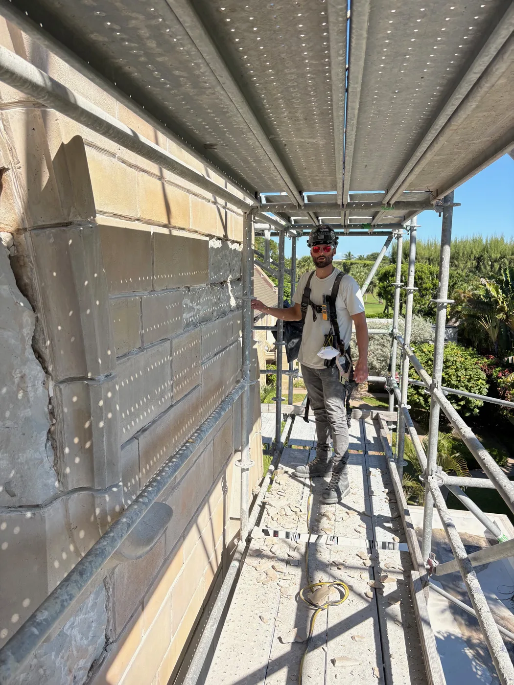 An Anthony Pennacchi & Sons mason on the scaffolding beside the repaired stone wall at Bethesda-by-the-Sea in Palm Beach, Florida